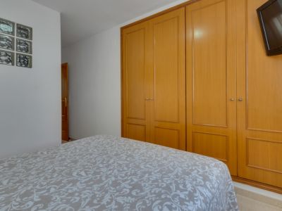 Helles Schlafzimmer mit Doppelbett und Einbauschrank aus Holz. Funktionale, minimalistische Einrichtung.