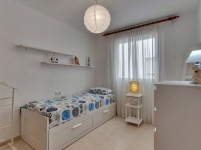 Helles Schlafzimmer mit Einzelbett, dekorativen Regalen und nautischen Akzenten.
