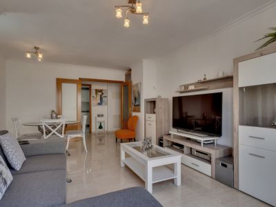 Helles Wohnzimmer mit Fliesenboden, grauem Sofa und modernen Möbeln in neutralen und weißen Tönen.