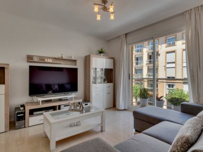 Helles Wohnzimmer mit modernen Möbeln und Balkonzugang mit Stadtblick.