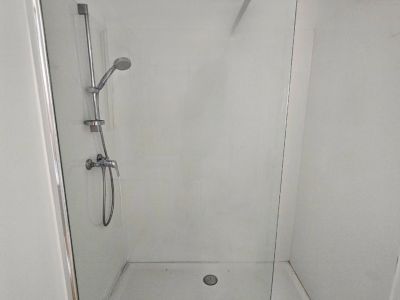 Detail der Dusche mit Glaswand und Stahlarmaturen in einem modernen Badezimmer.