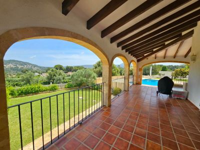 Überdachte Terrasse mit Steinbögen und Blick auf Garten und Pool.