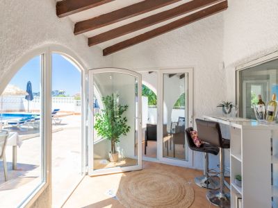 Detail der Bar im Innenbereich mit Poolblick und sichtbaren Holzbalken an der Decke.