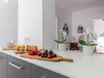 Detail der Küchentheke mit Obst und Blumen, das ein helles, modernes Design zeigt.