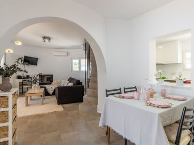 Helles Esszimmer mit gedecktem Tisch in Rosatönen und Zugang zum gewölbten Wohnzimmer.
