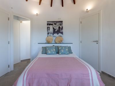 Helles Schlafzimmer mit Doppelbett, rosa Bettwäsche und einem mit Fächern dekorierten Kopfteil.