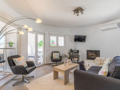 Helles Wohnzimmer mit dunkelgrauem Sofa, Ledersesseln und integriertem Kamin.