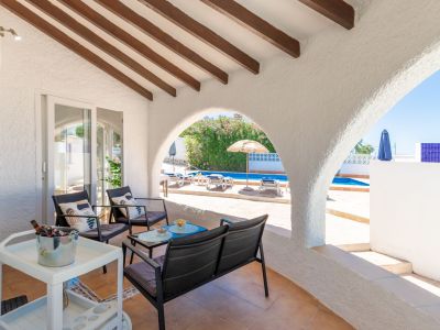 Überdachte Terrasse mit Poolblick und sichtbaren Holzbalken.