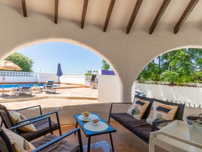 Überdachte Veranda mit Blick auf den Pool und den Garten, ideal zum Entspannen im Freien.