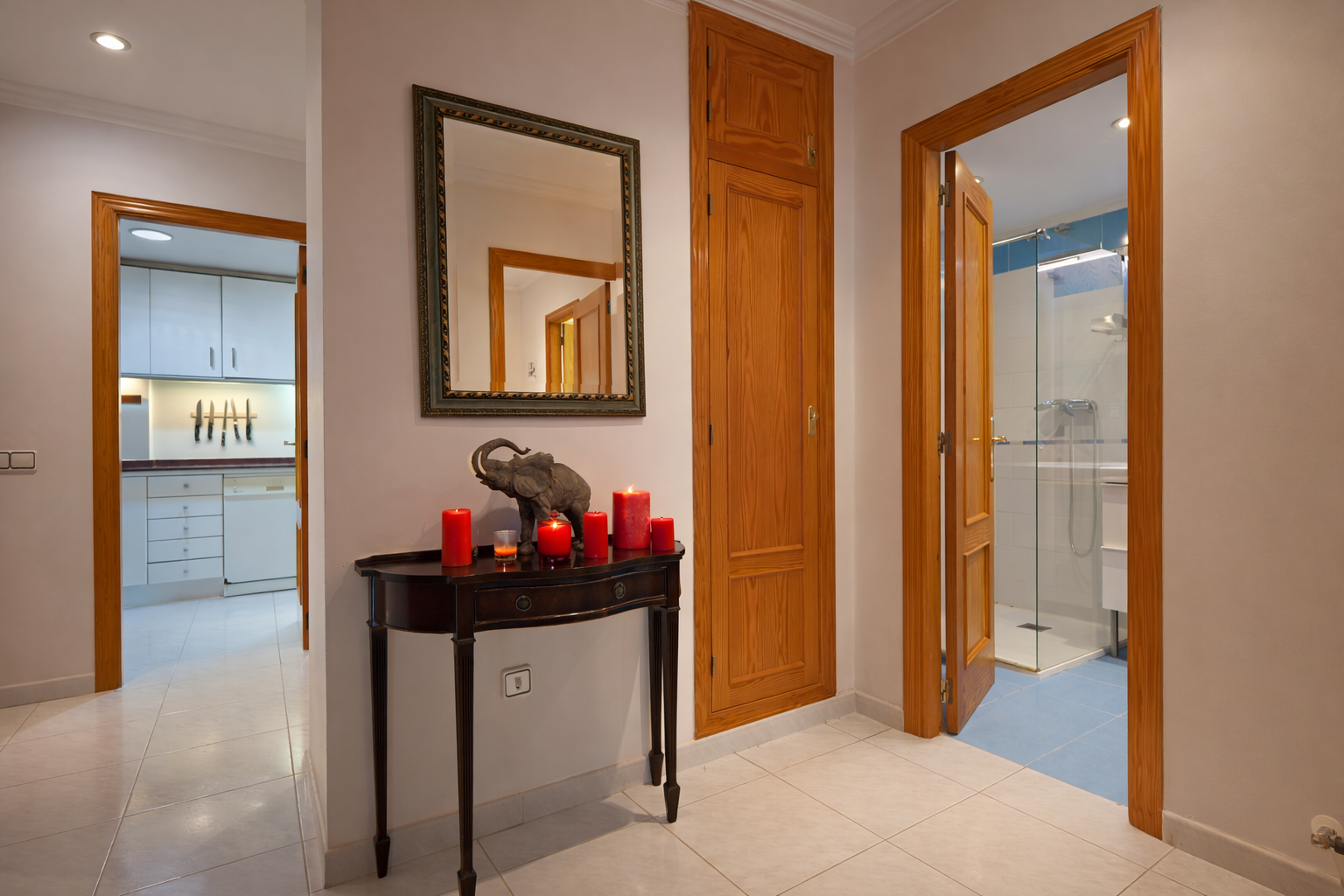 Flurdetail mit Holzkonsolentisch, Spiegel und Zugang zum Badezimmer.