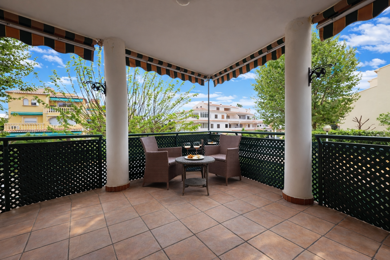 Überdachte Terrasse mit Fliesenboden und Blick auf Wohngebäude.