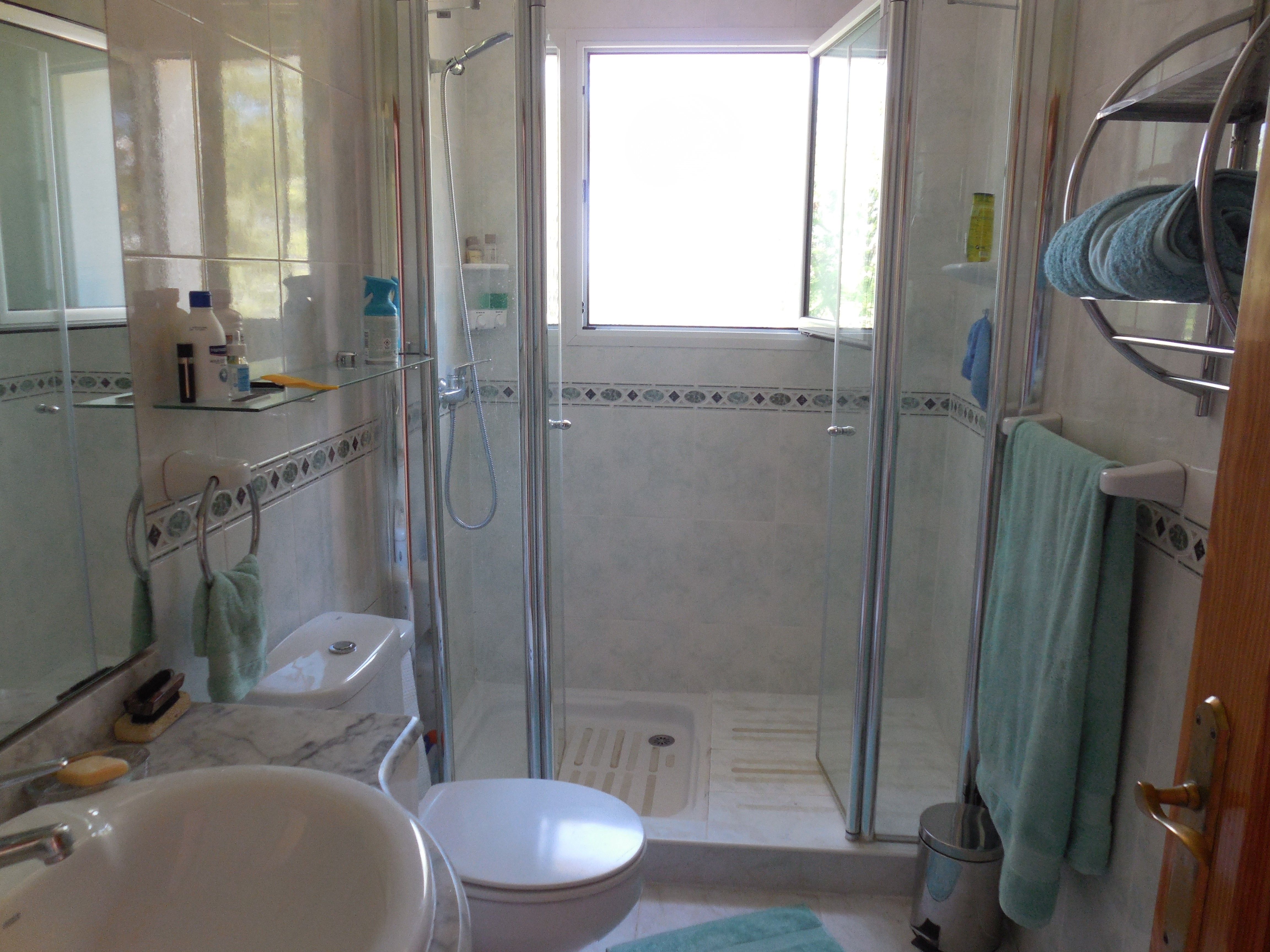 Badezimmer mit gläserner Duschkabine, Marmorwaschtisch und dekorativen Fliesenakzenten.