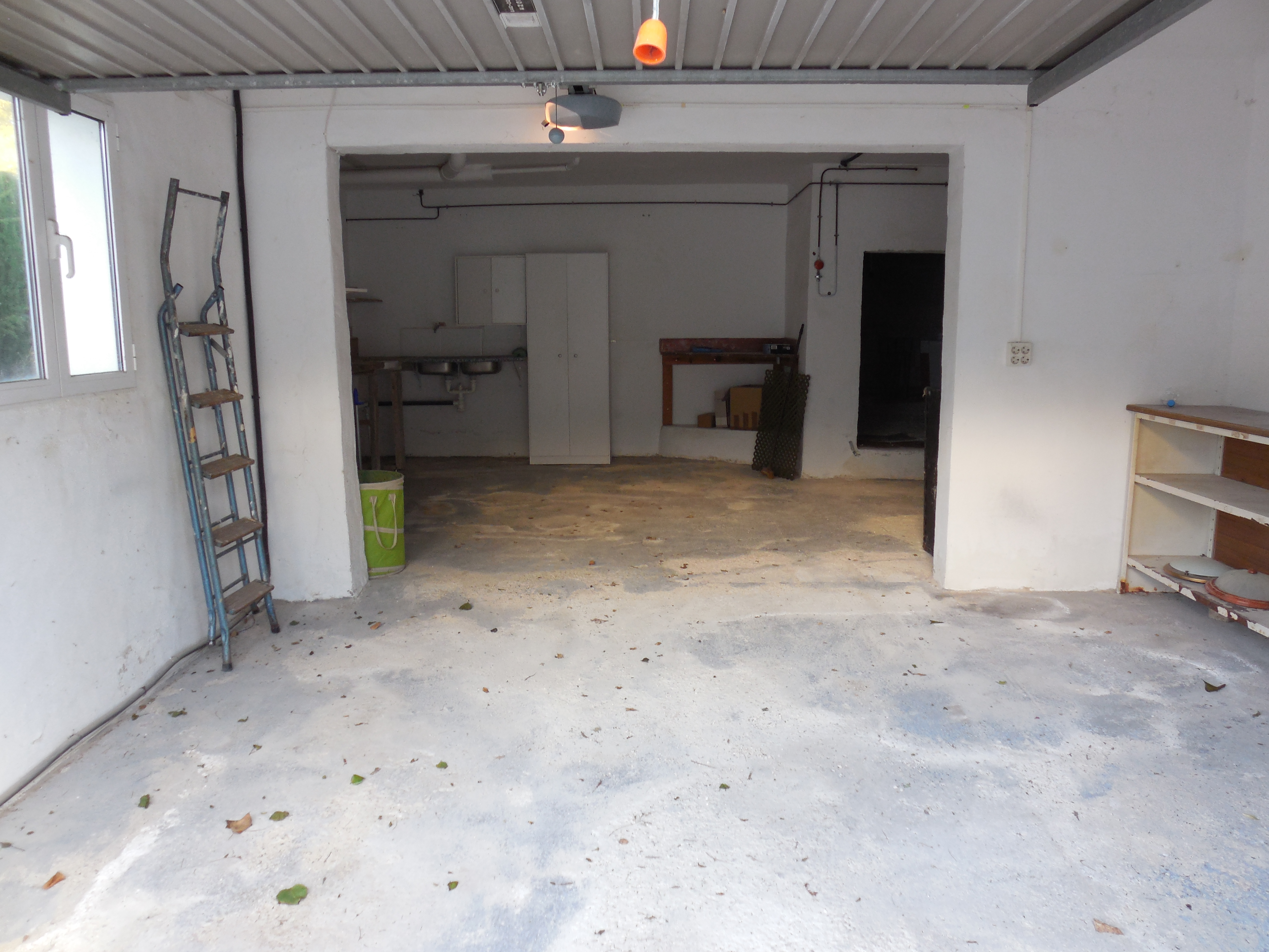 Garage mit Betonboden, weißen Wänden und Metallregalen.