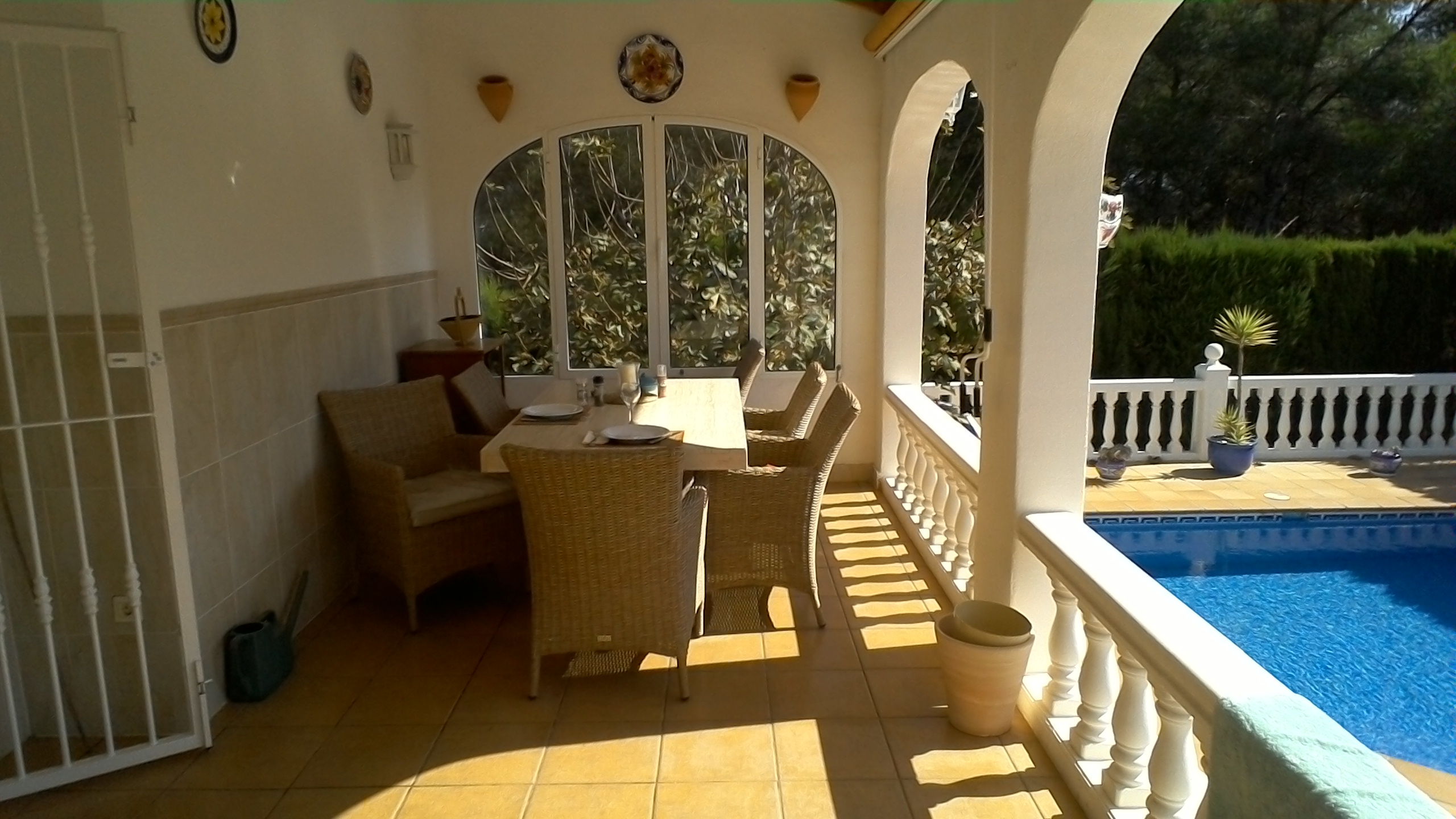 Überdachter Essbereich im Freien mit Blick auf den Pool und den Garten.