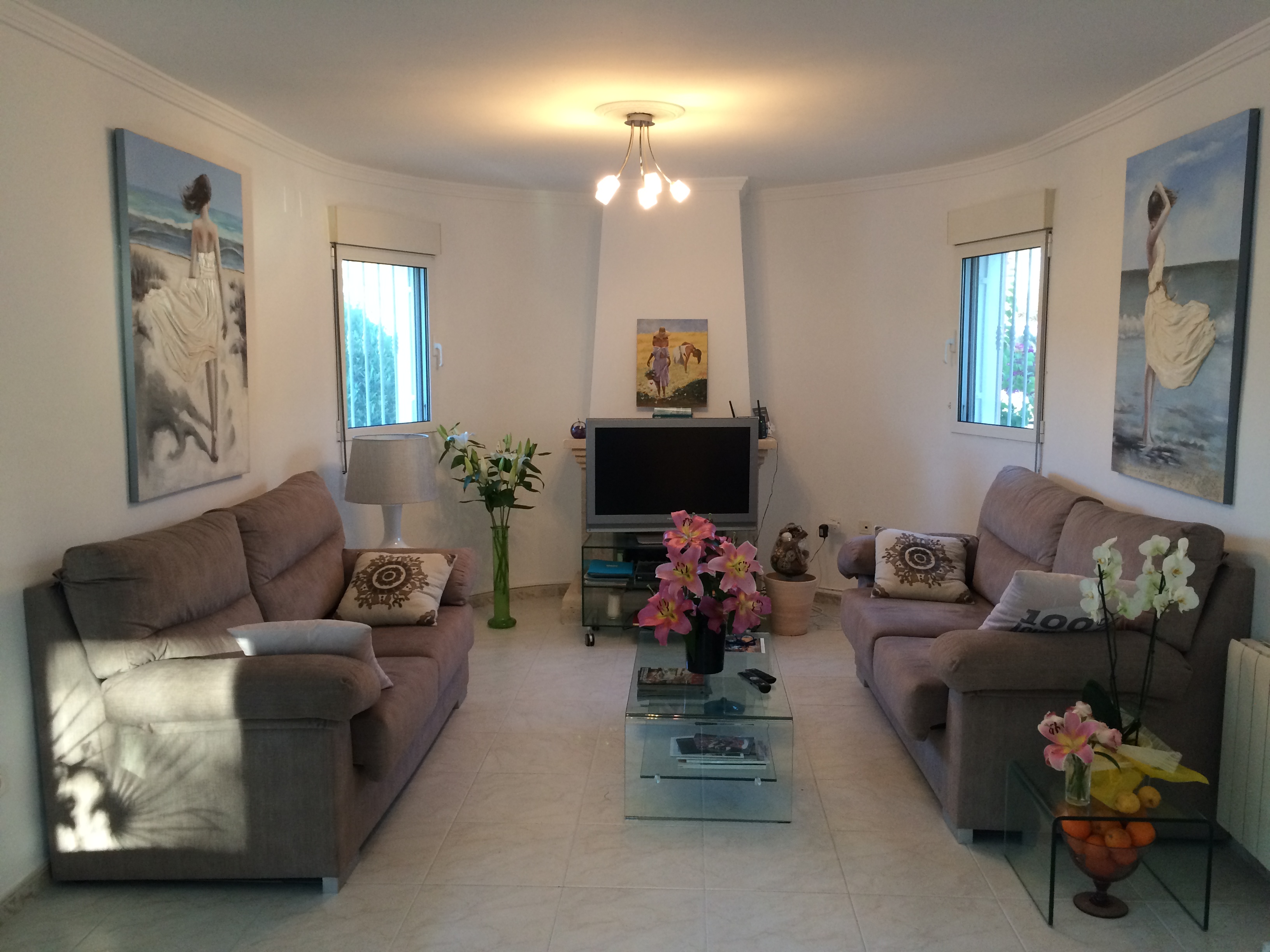 Wohnzimmer mit Stoffsofas, Couchtisch aus Glas und Blumendekoration.