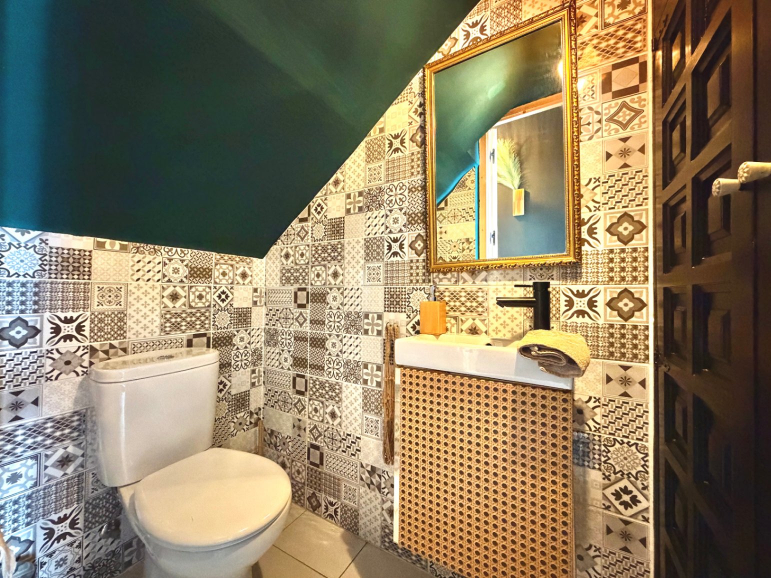 Gäste-WC mit gemusterten Fliesen, dunkelgrüner Decke und Waschtisch mit Korbfront.