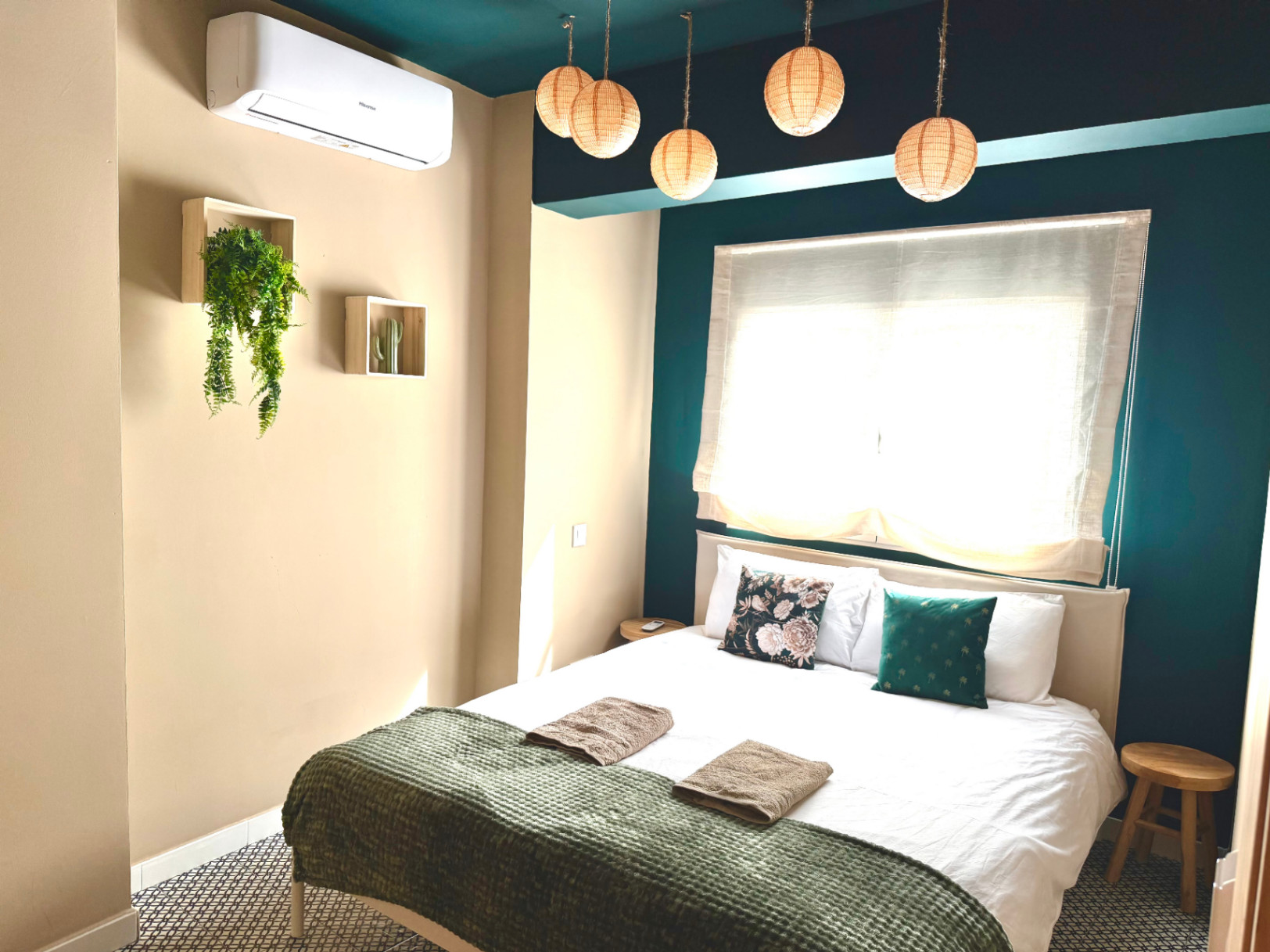 Schlafzimmer mit cremefarbenen Wänden und blaugrünen Akzenten. Hängelampen und minimalistisches Dekor.