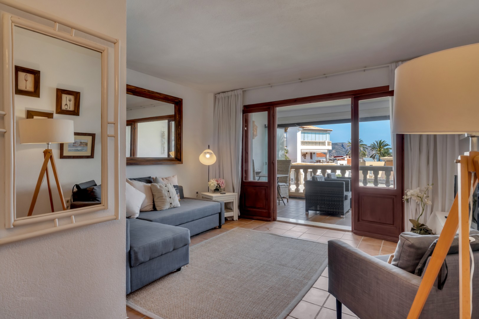 Helles Wohnzimmer mit verglaster Terrasse und Meerblick in Jávea. Graues Sofa und moderne Deko.