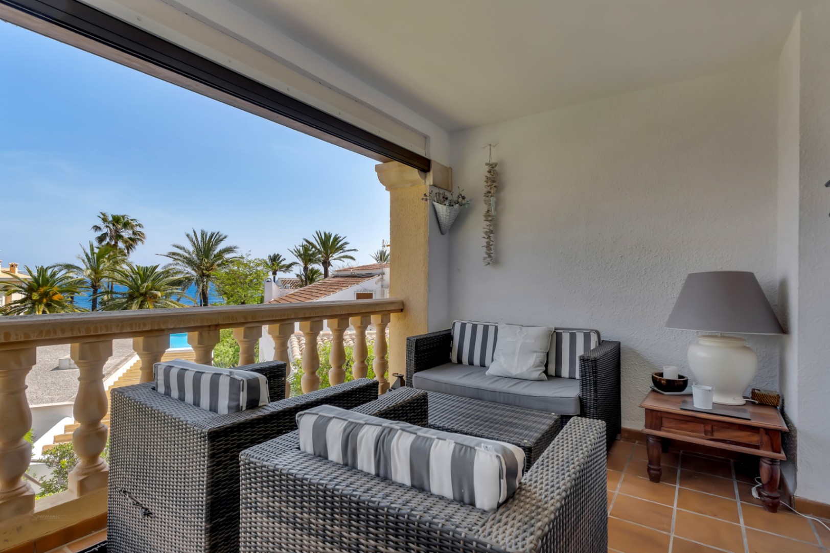 Terrasse mit Meerblick, möbliert mit Korbsesseln und gestreiften Kissen, ideal zum Entspannen.
