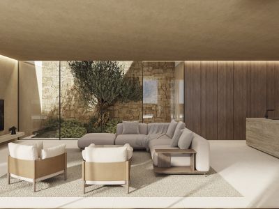 Moderner Wohnraum mit bodentiefen Fenstern, Blick auf Steinmauer und Olivenbaum. Mit modularem Sofa, Sesseln und einer Steininsel mit Wasserhahn, ergänzt durch lineare Deckenbeleuchtung.