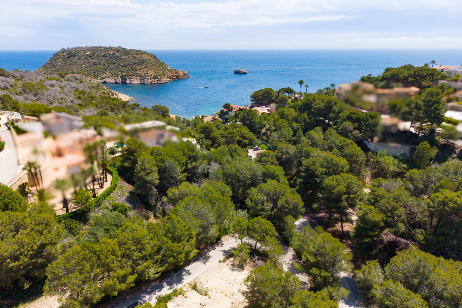 Luftaufnahme des bewaldeten Grundstücks mit Straßenzugang, mit Blick auf das Meer und die Landzunge in Jávea.