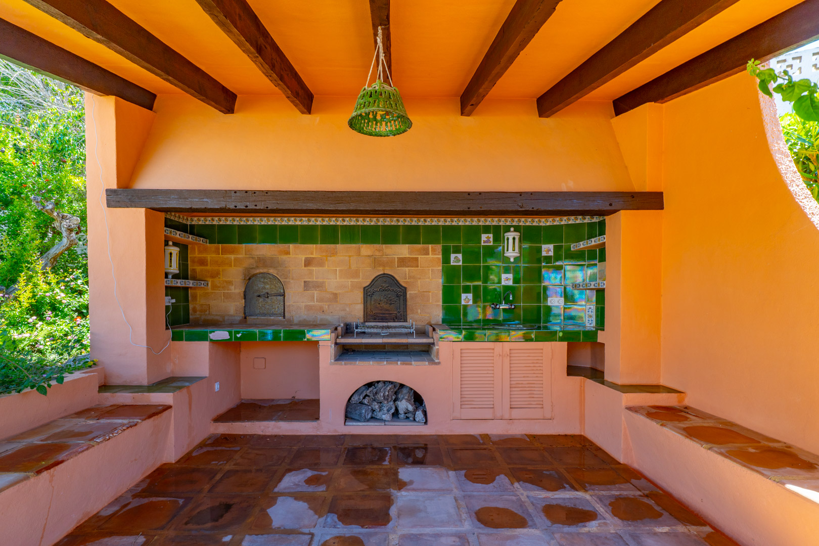 Grillplatz im Freien mit Holzofen, Spüle und Terrakottaboden.