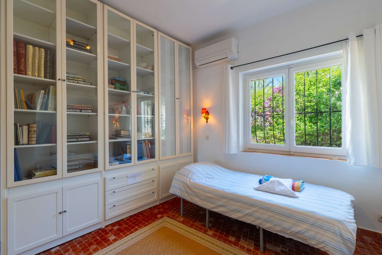 Helles Schlafzimmer mit Einbauregalen und Gartenblick.