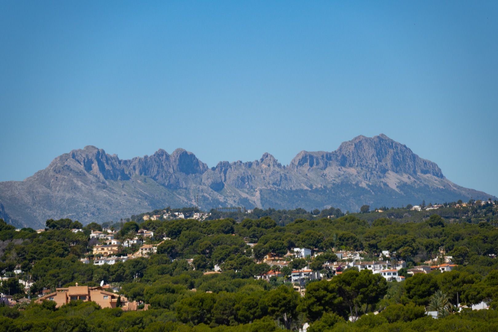 Panoramablick auf die Sierra de Bernia von der Villa aus, umgeben von Grün und anderen Wohnhäusern.