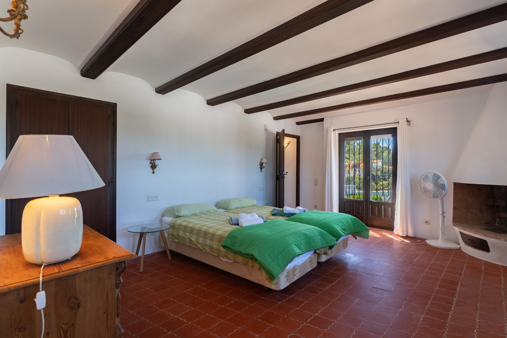 Schlafzimmer mit Einzelbetten, Holzbalken und Terrakottafliesen.