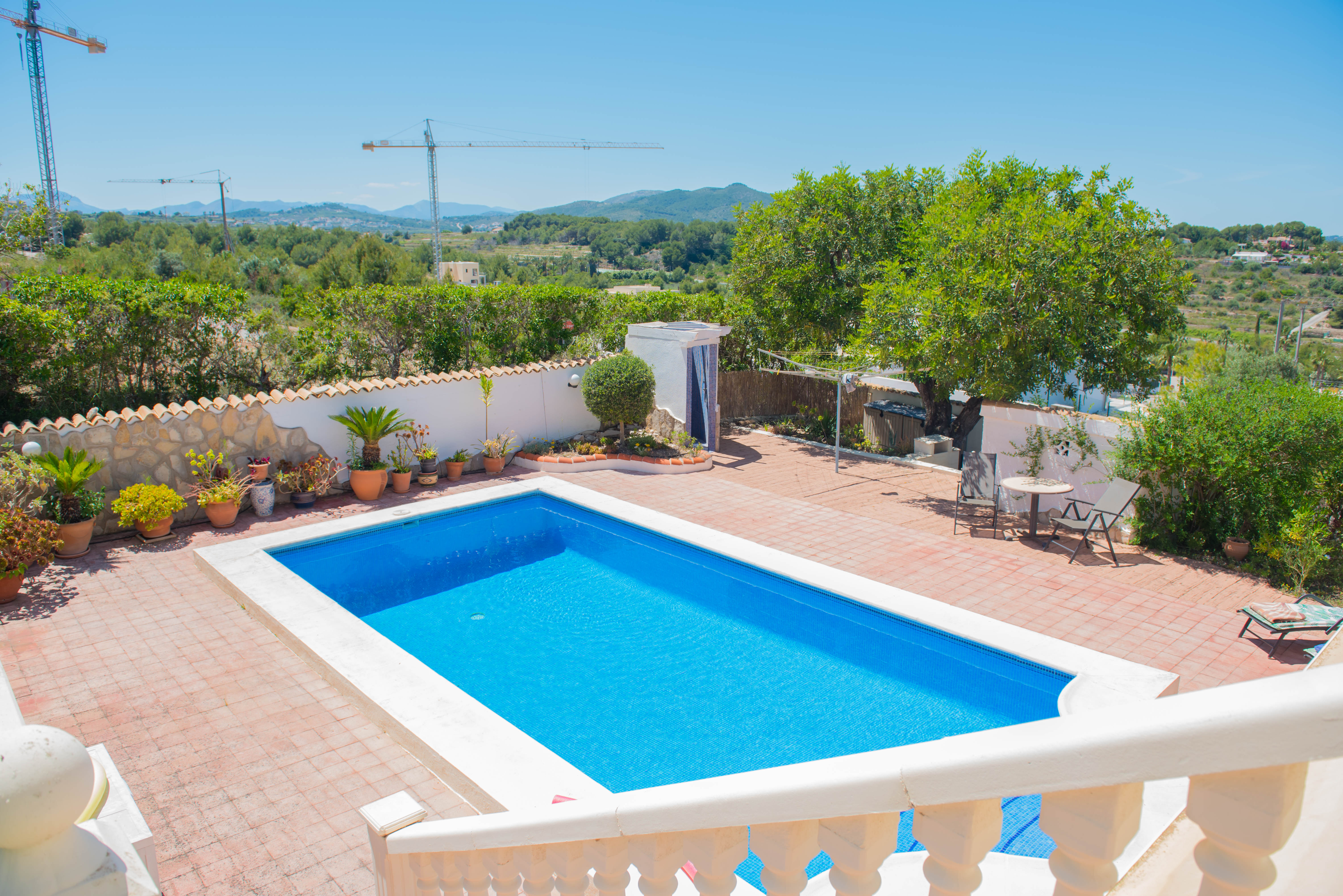 Erhöhte Ansicht des rechteckigen Pools mit weißer Umrandung und rot gefliester Terrasse.