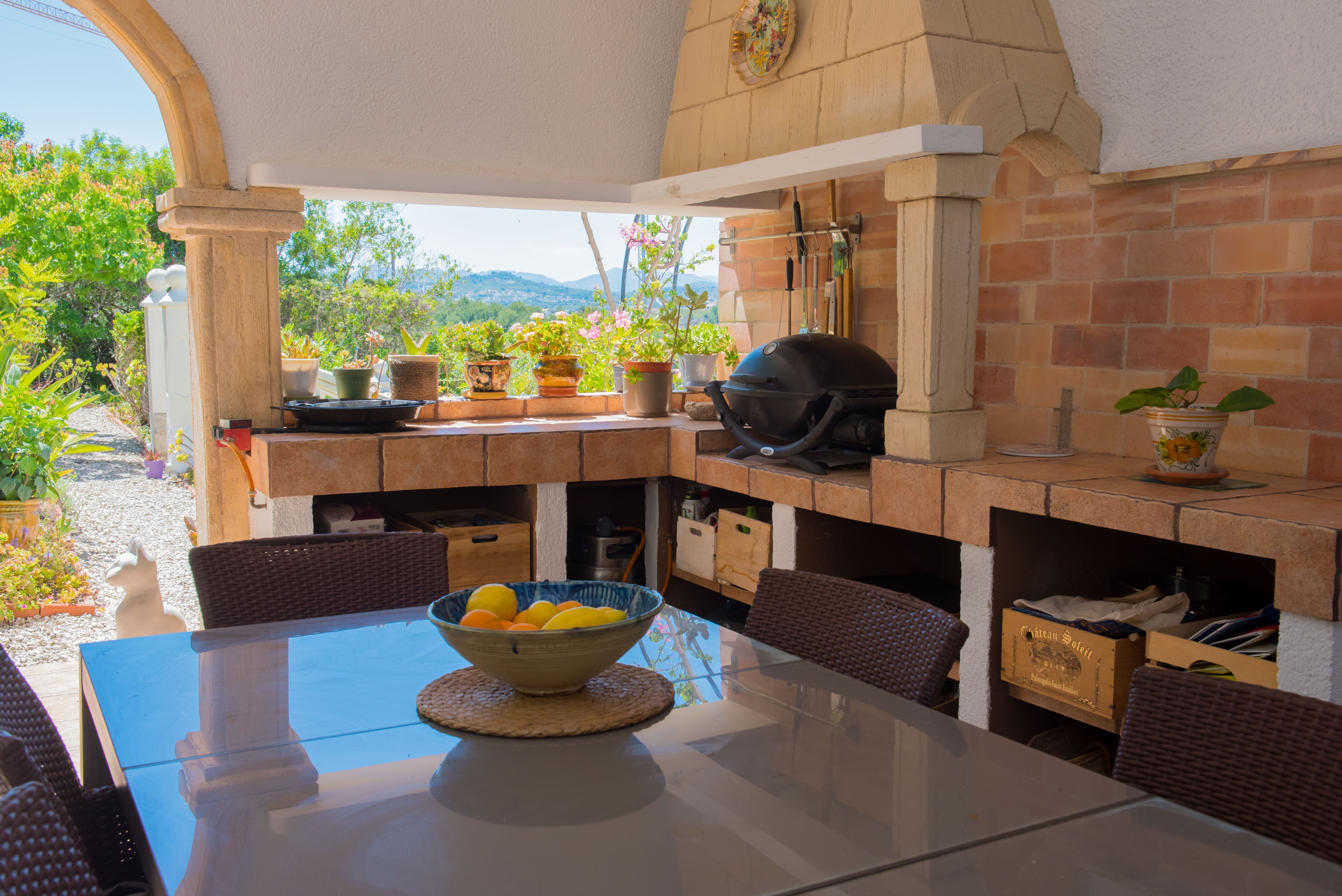 Grillplatz im Freien mit Backofen aus Ziegeln und Esstisch mit Blick auf den Garten.