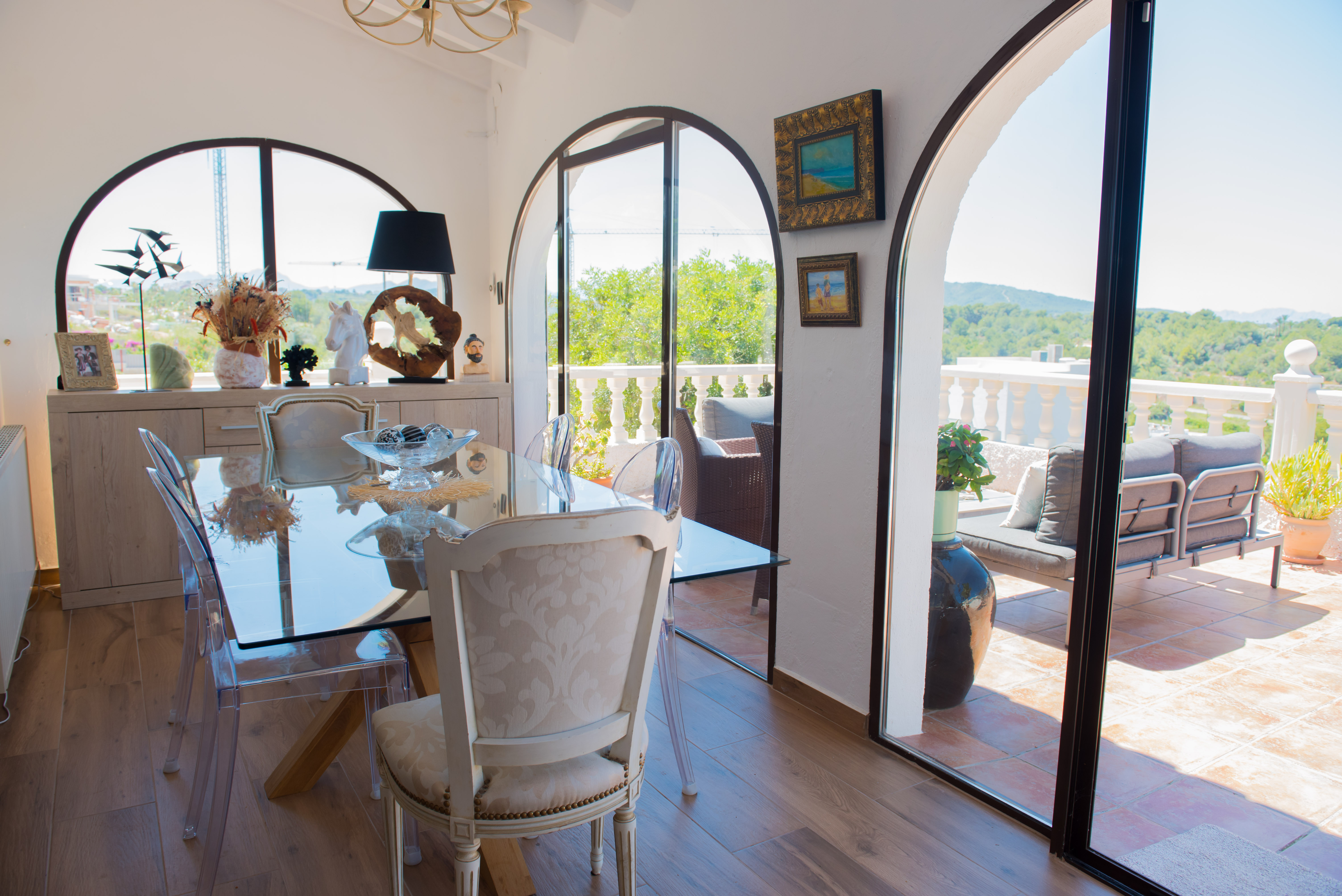 Heller Essbereich mit Glastisch und Zugang zu einer Terrasse mit Waldblick.