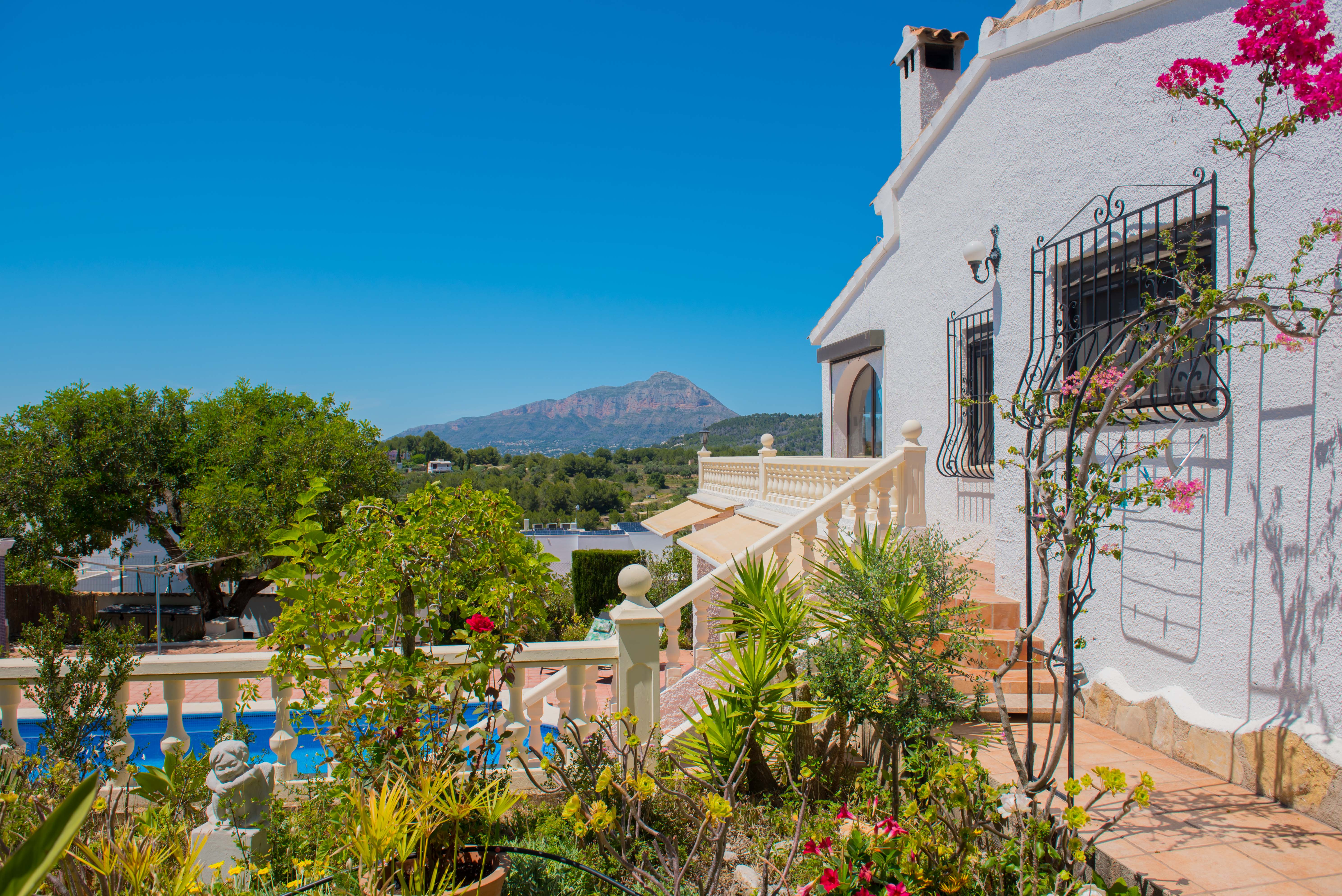 Mediterraner Garten mit Pool und Bergblick von der Terrasse.