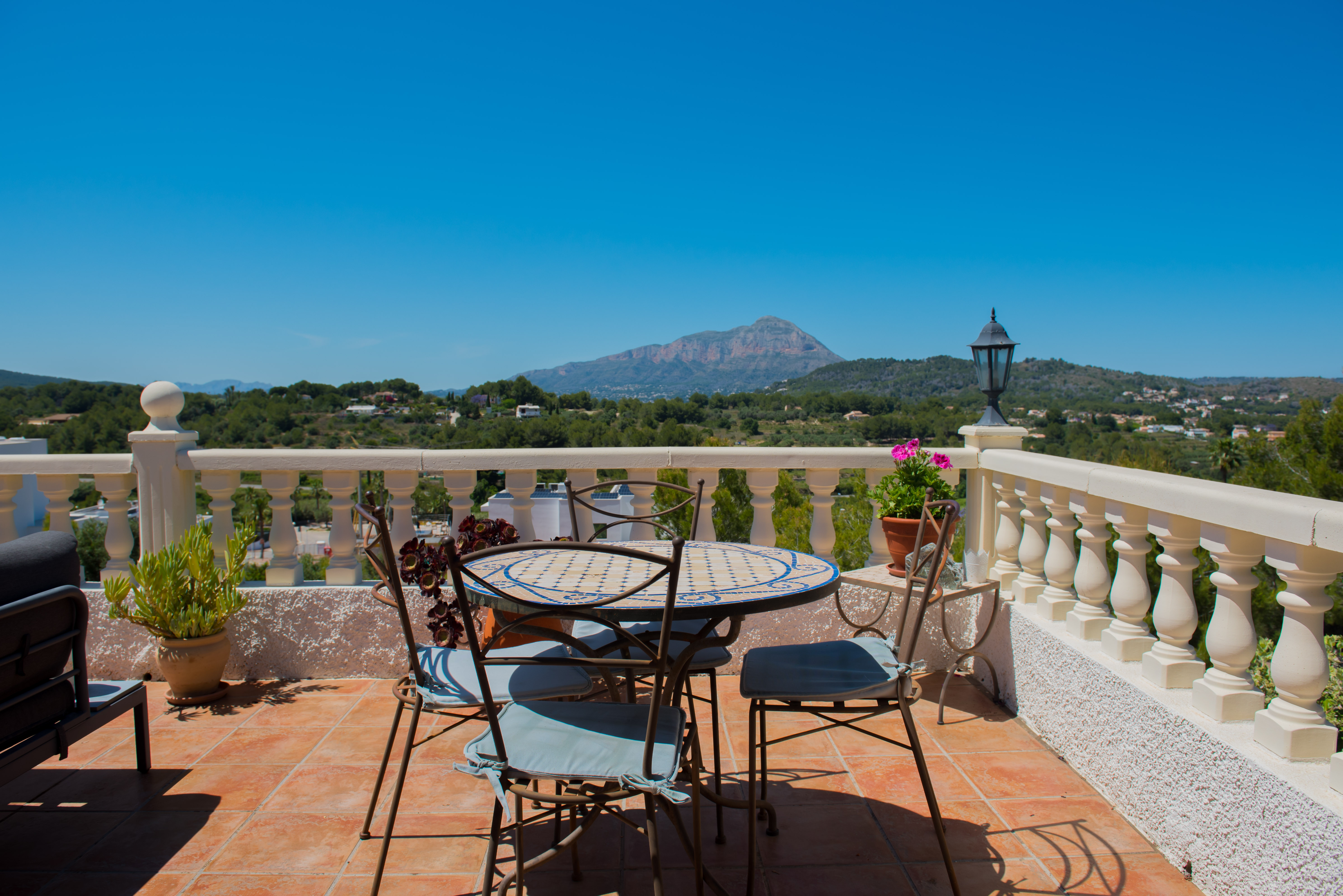 Terrasse mit Mosaiktisch und Bergblick.