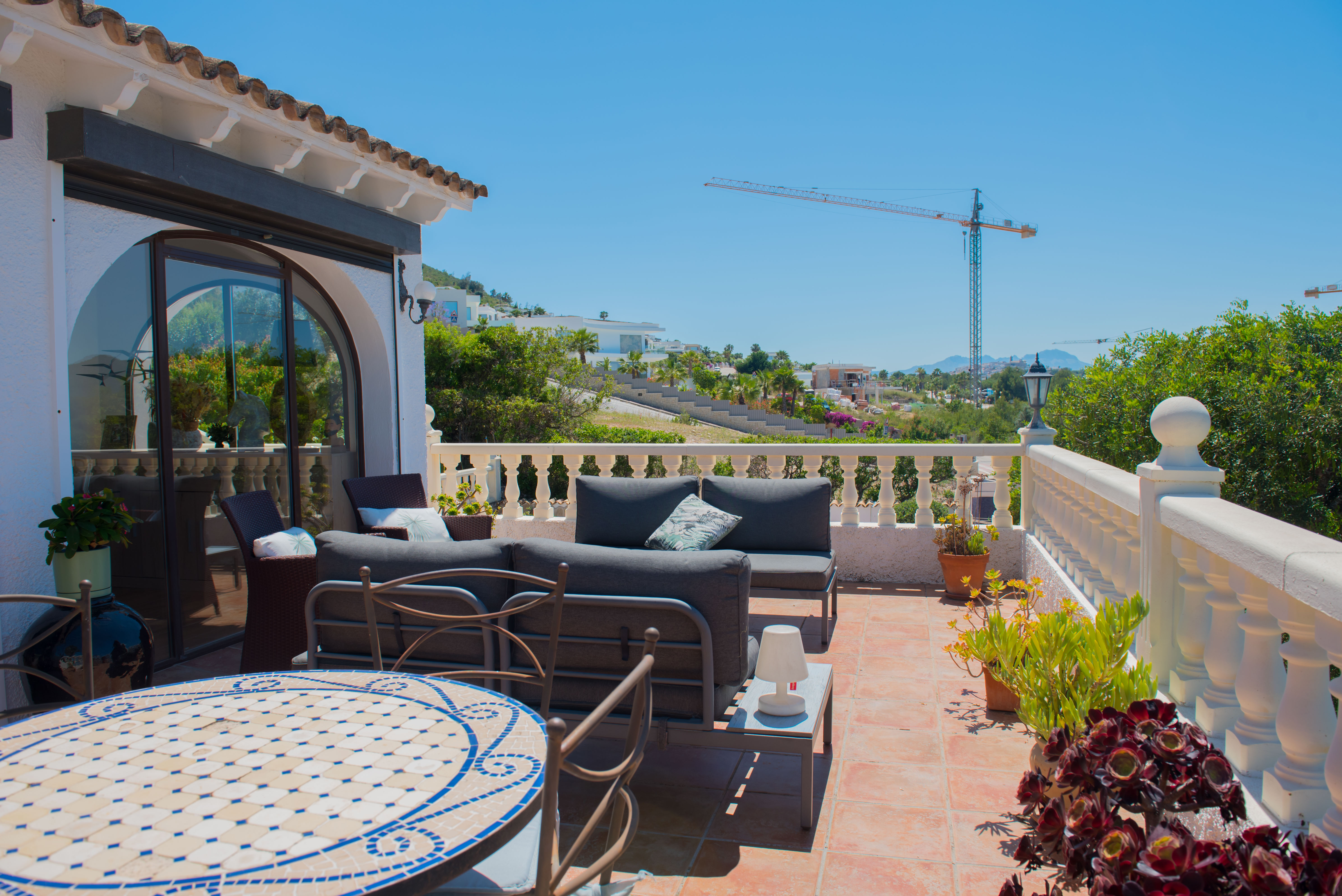 Terrasse mit Terrakottafliesen, weißer Balustrade und Panoramablick.