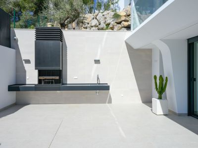 Moderne Außenküche mit integriertem Grill und Spüle auf hellen Fliesen. Ein Topfkaktus und natürliche Felslandschaft ergänzen den eleganten Außenbereich.