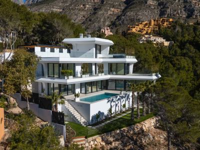 Moderne, mehrstöckige Villa mit integriertem Rechteckpool und weitläufigen Glastterrassen, eingebettet in einen grünen Hang mit Bergblick.