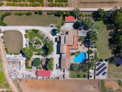 Detaillierte Luftaufnahme des weitläufigen Grundstücks, mit Hauptvilla, blauem Pool, Teich mit Insel und der Solaranlage.