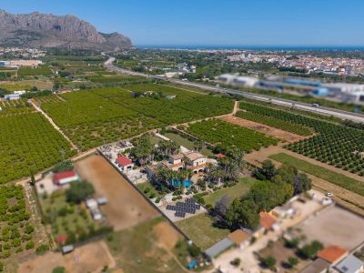 Luftaufnahme des Anwesens mit Haupthaus, Pool, weitläufigen Gärten und Solaranlage, umgeben von Orangenplantagen mit Meer- und Bergblick.