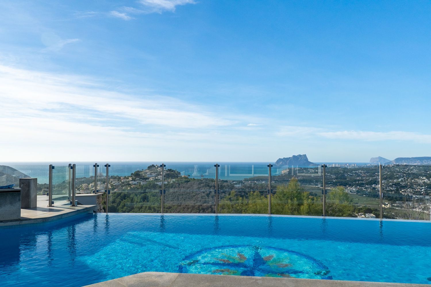 Der Infinity-Pool mit markantem Zentralmosaik verschmilzt optisch mit dem Horizont. Er bietet Panoramablicke auf das Meer, die Küste und den ikonischen Peñón de Ifach.