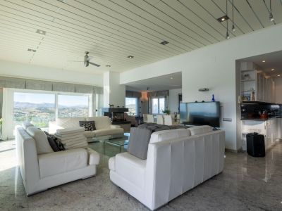 Heller Wohn-Essbereich mit weißen Ledersofas, Marmorboden und großen Fenstern mit Panoramablick auf die Berge. Die offene Küche verfügt über dunkle Granitarbeitsplatten.