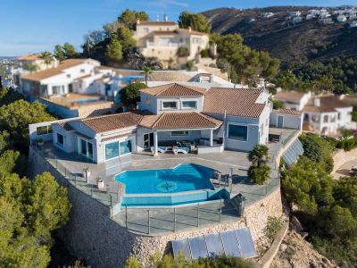 Luftaufnahme der Villa mit Infinity-Pool, Kompass-Mosaik und großzügiger Terrasse mit Glasgeländer. Charakteristisch sind die Ziegeldächer und Steinmauern in Hanglage.