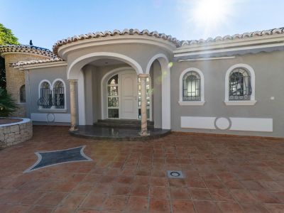 Haupteingang der Villa mit geschwungener Veranda, Marmorsäulen und weißen Bögen. Rundbogenfenster mit schmiedeeisernen Gittern und Terrakotta-Pflasterung.