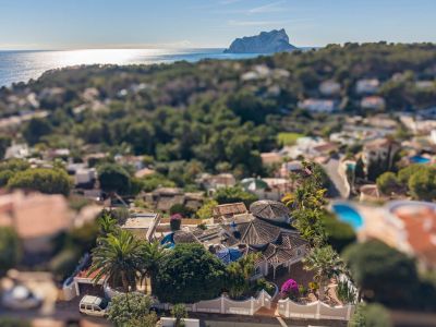 Luftaufnahme der Villa mit ihren markanten Ziegeldächern, eingebettet in üppige mediterrane Gärten. Im Hintergrund erstreckt sich der Panoramablick auf das Meer und den Peñón de Ifach.