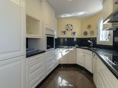 Separate Küche mit weißen Schränken, dunklen Granitarbeitsplatten und Spritzschutz. Sie verfügt über einen Einbaubackofen, Spüle und ein gewölbtes Fenster für Tageslicht.