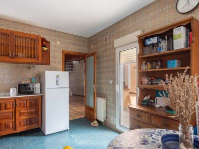 Küche mit blauen Bodenfliesen und gemusterten Wandfliesen. Ausgestattet mit Holzschränken, Kühlschrank und direktem Terrassenzugang.