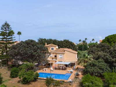 Luftaufnahme der zweistöckigen Villa mit Ziegeldach, die den blauen Pool, die gepflasterte Terrasse mit Pergola und den weitläufigen mediterranen Garten zeigt.