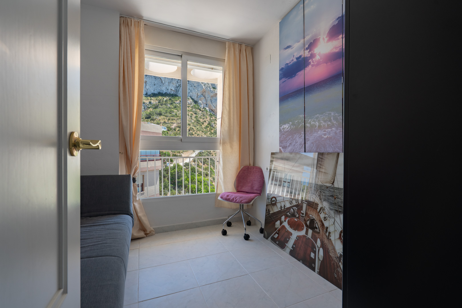 Zusätzliches Schlafzimmer oder Arbeitszimmer mit Bergblick, ausgestattet mit Sofa, Bürostuhl und hellem Fliesenboden. Dekoriert mit maritimer Kunst und einem dunklen Kleiderschrank.