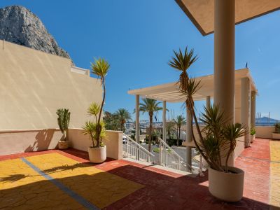 Außenterrasse mit mediterranen Pflanzen, gemusterten rot-gelben Fliesen und freiem Blick auf den Peñón de Ifach und den Hafen von Calpe.
