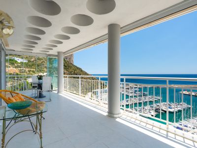 Geräumige, geflieste Terrasse mit einzigartigen runden Deckendetails, die einen Panoramablick auf den geschäftigen Hafen von Calpe und das Mittelmeer unter blauem Himmel bietet.